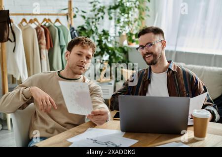 Deux hommes discutant des dessins et des croquis à une table dans un atelier de designer. Banque D'Images