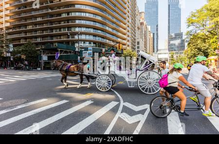 New York City, États-Unis - 24 août 2017 : septième Avenue à l'angle de W 59th Street, avec des gens sur un tandem vélo, une calèche et un piéton Banque D'Images