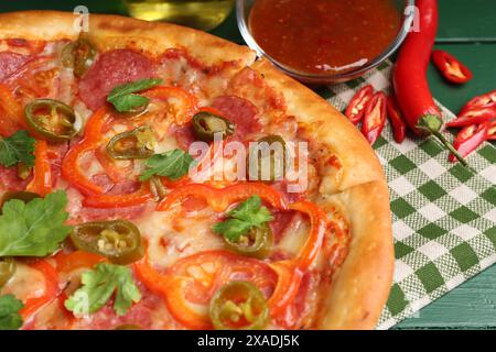 Délicieuse pizza Diablo et ingrédients sur la table en bois vert, gros plan Banque D'Images