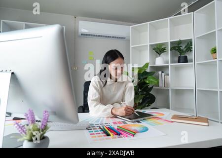 graphiste au travail dessiner des esquisses un nouveau projet sur tablette graphique et palette de couleurs assis au bureau avec ordinateur au studio ou au bureau Banque D'Images