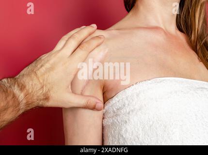 Homme main examine une cicatrice postopératoire sur une épaule de femme. Guérison des cicatrices, traitement des cicatrices sur la peau Banque D'Images