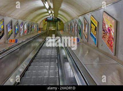 Métro londonien descendant les escaliers mécaniques typiques utilisés entre les stations Banque D'Images