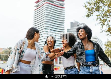 Un groupe diversifié de femmes est capturé au milieu du rire dans une ville moderne. Banque D'Images