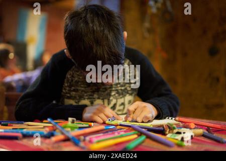 garçon latino dessinant avec des crayons dans un bar de nuit. Concept de divertissement sans écrans Banque D'Images