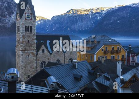 Photographie du centre-ville et de la cathédrale d'un vieux village autrichien de Hallstatt sur une montagne brumeuse rive d'un lac Banque D'Images