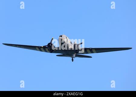 Un Douglas C47, connu sous le nom de Dakota dans la Royal Air Force et les services du Commonwealth, qui est devenu l'avion de transport le plus connu au monde et a été largement utilisé par les Alliés pendant la seconde Guerre mondiale, survole l'événement commémoratif national britannique pour le 80e anniversaire du jour J, à Ver-sur-mer, en Normandie, en France. Date de la photo : jeudi 6 juin 2024. Banque D'Images