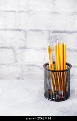 Ensemble de crayons simples lumineux dans un support noir sur une table grise, espace de copie Banque D'Images