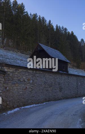 Photographie d'une petite cabane en bois sous les Alpes lors d'une soirée ensoleillée d'hiver Banque D'Images