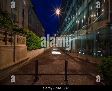 Ruelle urbaine éclairée à Zurich, en Suisse, la nuit avec des bâtiments modernes et classiques, des buissons verts, des étoiles légères Banque D'Images