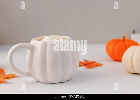 Boisson chaude dans une tasse en forme de citrouille, composition de nature morte d'automne Banque D'Images