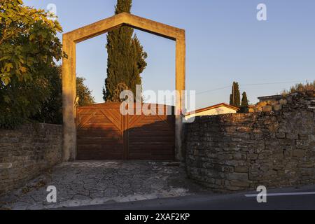 Photo d'une rue de village avec des portes en bois et des arbres sur la lumière chaude du coucher du soleil d'été Banque D'Images