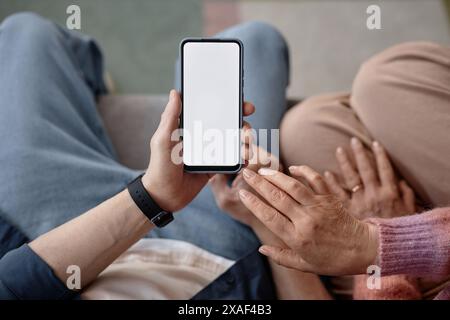 Vue de dessus gros plan d'un couple senior tenant un smartphone avec une maquette d'écran blanc vierge et utilisant l'espace de copie de l'application mobile Banque D'Images