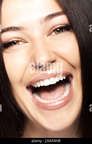 Vue rapprochée du visage d'une femme avec la bouche ouverte montrant ses dents. Fille parlant ou criant ou chantant. En regardant la caméra. Banque D'Images