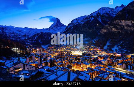 Vue aérienne hivernale du village de Zermatt la nuit, dominée par le pic du Cervin dans les Alpes suisses - paysage idyllique avec chalets en bois sur Banque D'Images