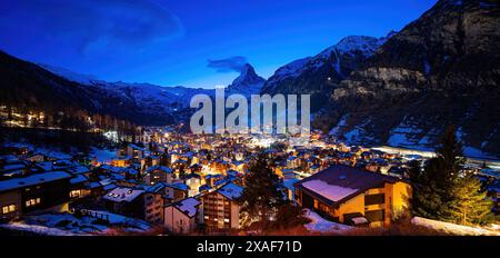 Vue aérienne hivernale du village de Zermatt la nuit, dominée par le pic du Cervin dans les Alpes suisses - paysage idyllique avec chalets en bois sur Banque D'Images