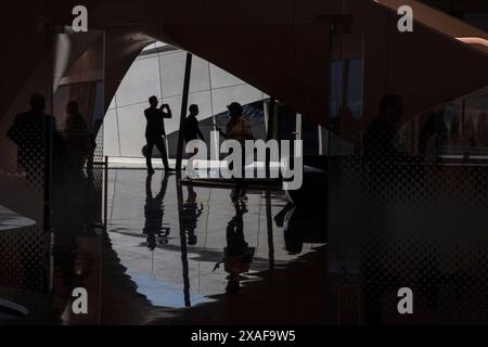 Quelqu'un marchant dans l'espace entre les bureaux et la salle de réception principale. Siège social de BEEAH, Sharjah, Émirats arabes Unis. Architecte : Zaha Banque D'Images
