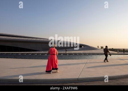 Les gens marchant passaient devant le grand étang à l'extérieur du bâtiment principal. Siège social de BEEAH, Sharjah, Émirats arabes Unis. Architecte : Zaha Hadid Architects, 2 Banque D'Images