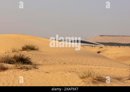 Une vue lointaine depuis le désert. Siège social de BEEAH, Sharjah, Émirats arabes Unis. Architecte : Zaha Hadid Architects, 2022. Banque D'Images