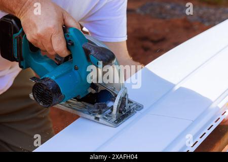 Artisan découpe des panneaux de parement en vinyle à la taille désirée avant de les installer sur la façade de son projet de construction Banque D'Images