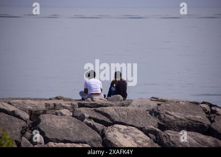 Couple assis sur un brise-lames dans le lac Ontario Banque D'Images