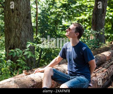 Portrait d'un homme actif de 40 ans, assis sur des troncs d'arbres dans le bois, Burg-Reuland, Belgique. Autorisation du modèle. Banque D'Images