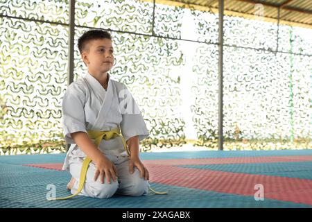 Enfants dans un kimono assis sur le tatami à l'extérieur. Pratique de karaté Banque D'Images