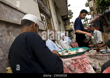 Hommes égyptiens appréciant le petit déjeuner égyptien dans un petit restaurant de rue à Alexandrie, Egypte. Banque D'Images