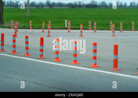 Une rangée de cônes orange et blanc sont alignés sur une route. Les cônes sont espacés et ne sont pas utilisés Banque D'Images