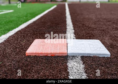 Vue du terrain de softball synthétique pour l'école secondaire, première base avec deuxième base de sécurité orange, en regardant vers la plaque d'accueil. Banque D'Images