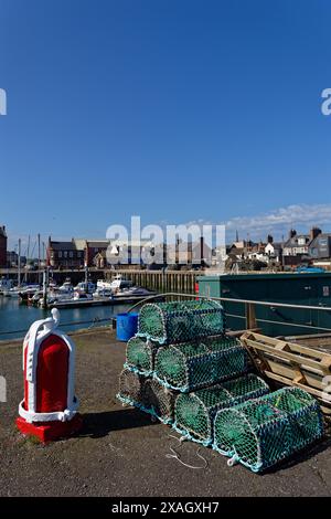 Une vieille borne traditionnelle peinte en rouge à côté des pots de homard et de crabe au bord du quai dans le port intérieur et la marina d'Arbroath. Banque D'Images