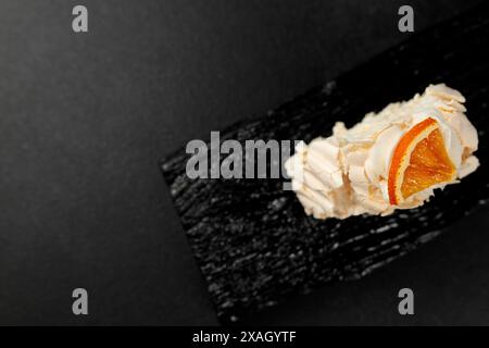 Rouleau de meringue. Protéines fouettées et sucre, garniture - fromage à la crème à base de fromage à pâte molle et de crème sur une planche à découper noire Banque D'Images