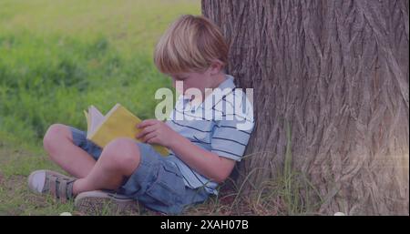 Image de traînées de lumière sur un livre de lecture de garçon caucasien Banque D'Images