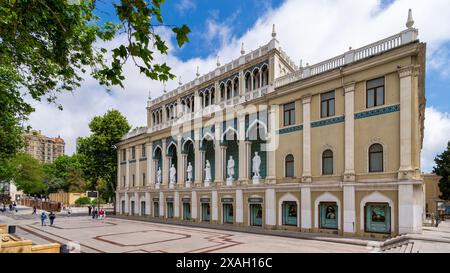 Bakou, Azerbaïdjan - 5 mai 2024 : Musée Nizami d'Azerbaïdjan, avec des statues bordant la façade. Le bâtiment est décoré avec des arches et des carreaux complexes. On peut voir des gens marcher près du bâtiment Banque D'Images