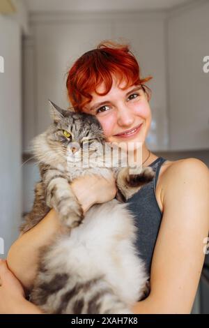 portrait jeune fille aux cheveux rouges avec chat pelucheux gris Banque D'Images