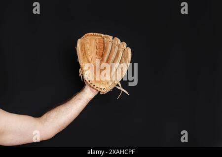 Gant de baseball sur la main de l'homme. Fond noir. Sports actifs, championnat, victoire, compétition Banque D'Images