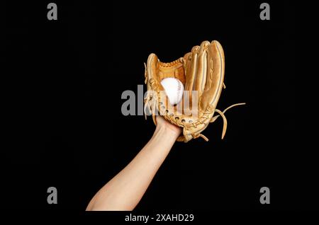 Main en cuir marron gant de baseball attrape la balle. Fond noir. Sports actifs, championnat Banque D'Images