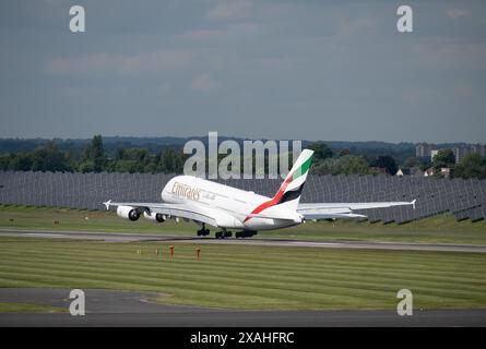 Airbus A380-861 d'Emirates décollant à l'aéroport de Birmingham avec des panneaux solaires derrière lui, Royaume-Uni Banque D'Images