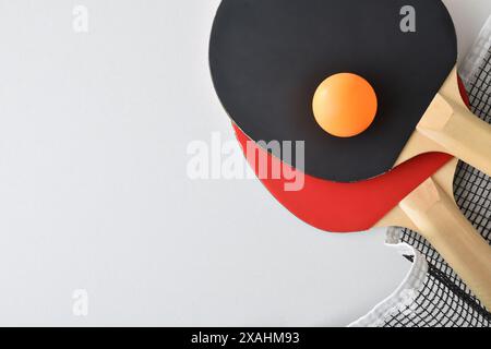 Fond avec ensemble de raquettes de tennis de table, filet et balle orange isolé sur table blanche. Vue de dessus. Banque D'Images