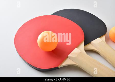 Ensemble de raquettes de tennis de table et deux balles orange isolées sur table blanche. Vue surélevée. Banque D'Images