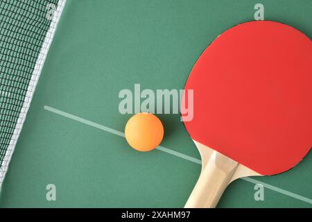 Pagaie de ping-pong et balle orange sur la table de jeu verte. Vue de dessus. Banque D'Images