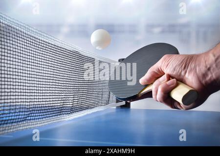 Détail d'une personne jouant au ping-pong sur une table bleue dans un pavillon sportif. Vue de face. Banque D'Images