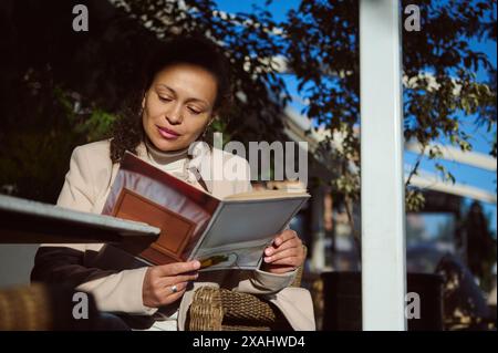 Une femme profite d'une journée d'hiver sereine dans un café de Marrakech, lisant un magazine et profitant du soleil. Banque D'Images