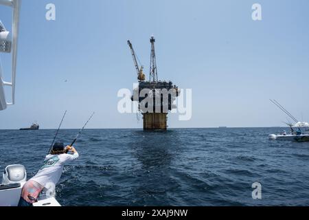 Un pêcheur à la ligne défile dans un thon capturé près de plates-formes pétrolières flottantes dans le golfe du Mexique, illustrant la juxtaposition de la pêche récréative et du pétrole au large Banque D'Images