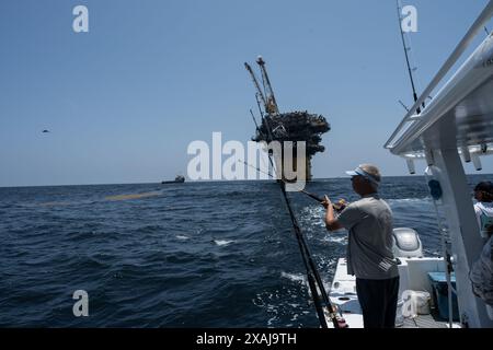 Un pêcheur à la ligne défile dans un thon capturé près de plates-formes pétrolières flottantes dans le golfe du Mexique, illustrant la juxtaposition de la pêche récréative et du pétrole au large Banque D'Images