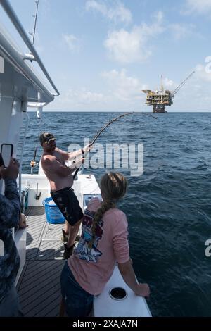 Un pêcheur à la ligne défile dans un thon capturé près de plates-formes pétrolières flottantes dans le golfe du Mexique, illustrant la juxtaposition de la pêche récréative et du pétrole au large Banque D'Images