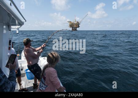 Un pêcheur à la ligne défile dans un thon capturé près de plates-formes pétrolières flottantes dans le golfe du Mexique, illustrant la juxtaposition de la pêche récréative et du pétrole au large Banque D'Images