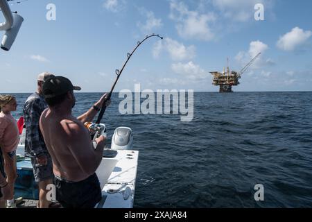 Un pêcheur à la ligne défile dans un thon capturé près de plates-formes pétrolières flottantes dans le golfe du Mexique, illustrant la juxtaposition de la pêche récréative et du pétrole au large Banque D'Images