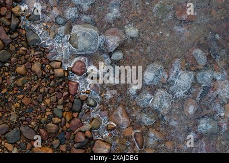 Flaque gelée sur gravier, texture de glace avec bulles d'air Banque D'Images