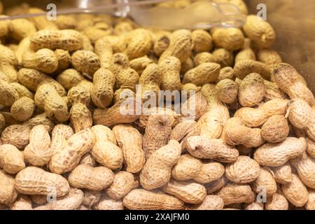 Un récipient en verre rempli d'arachides dans leurs coquilles disposées en pile, présentant une variété d'aliments naturels de la famille des légumineuses Banque D'Images
