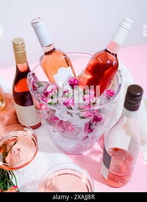 Mini roses congelées dans des glaçons dans un seau à vin avec des bouteilles de Banque D'Images